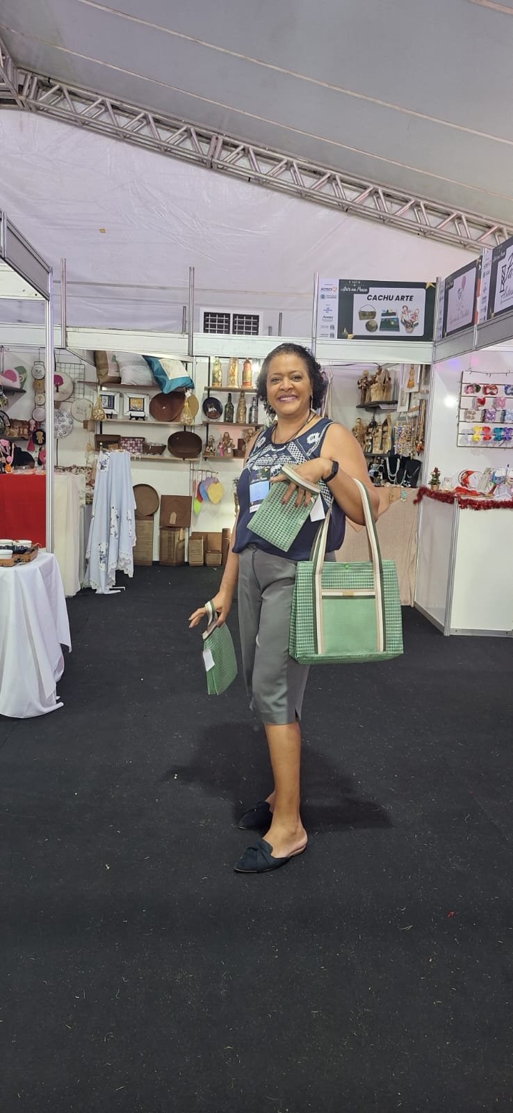 Cláudia Maciel na feira Art's na Praça, segurando bolsas de tecido verdes