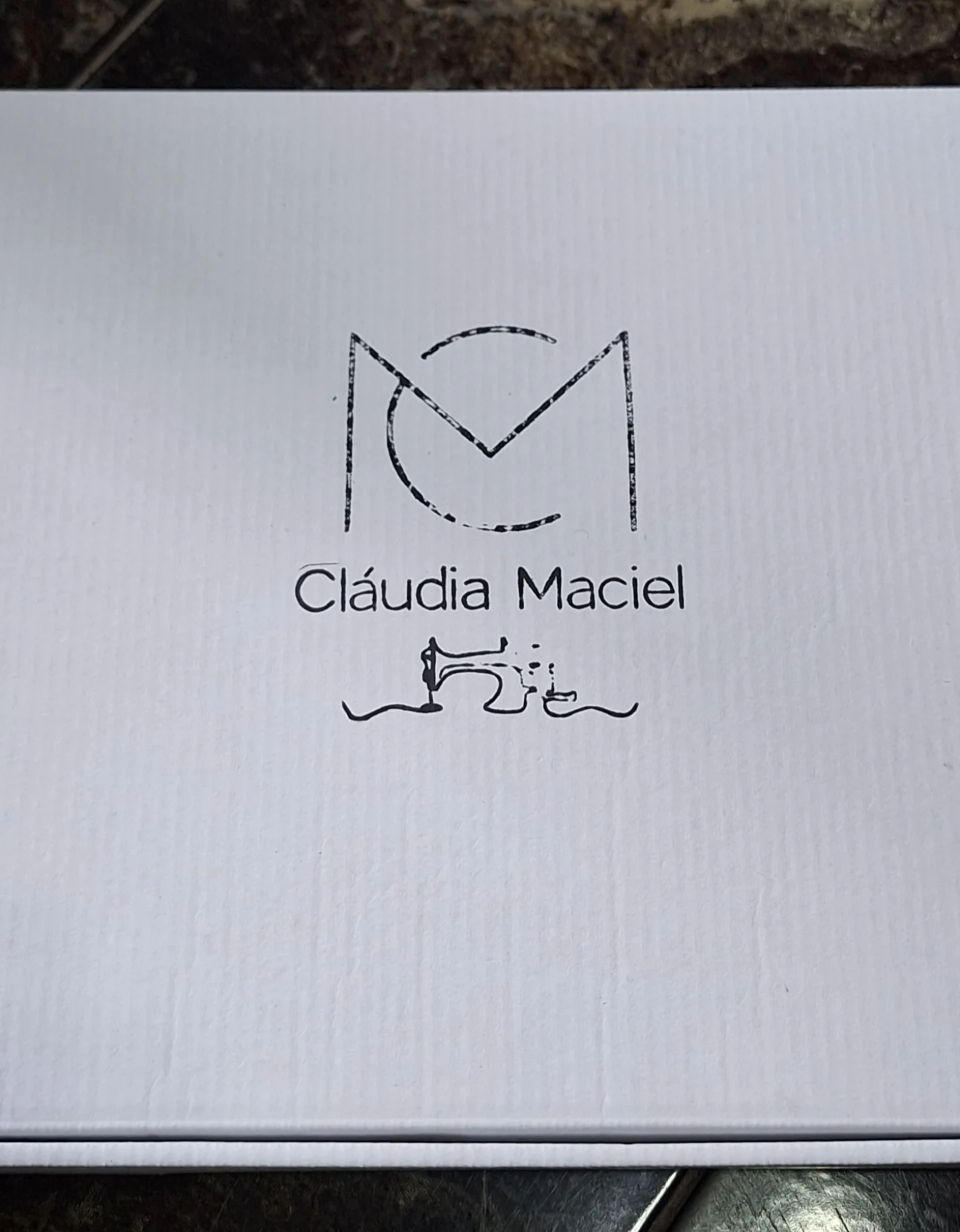 Caixa de embalagem com a marca Cláudia Maciel